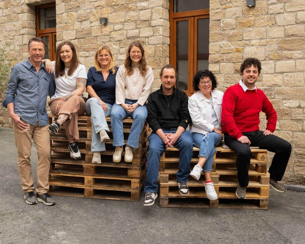 familie_schmitt_sitzend_paletten_hof_1_quer_1200x800 1 familie schmitt sitzend paletten hof 1 quer 1200x800 uai